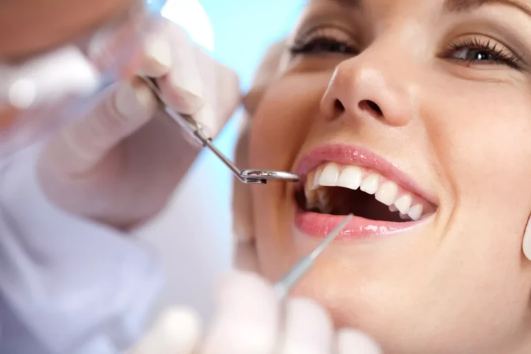 Dentist examining a smiling patient’s teeth with dental instruments during a checkup