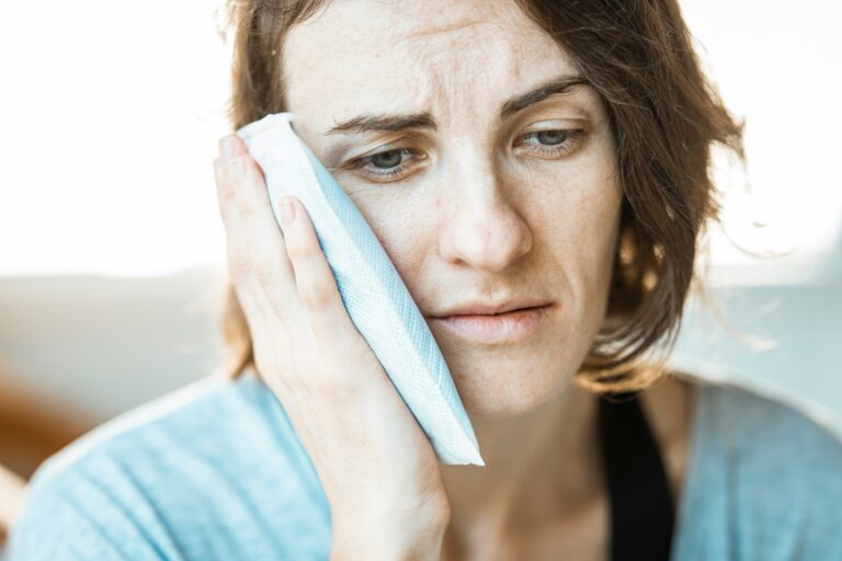 Woman applying a cold compress to her cheek to relieve tooth pain or dental swelling